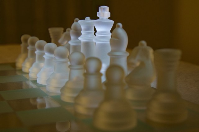 A glass chess board with white pieces sitting on it.